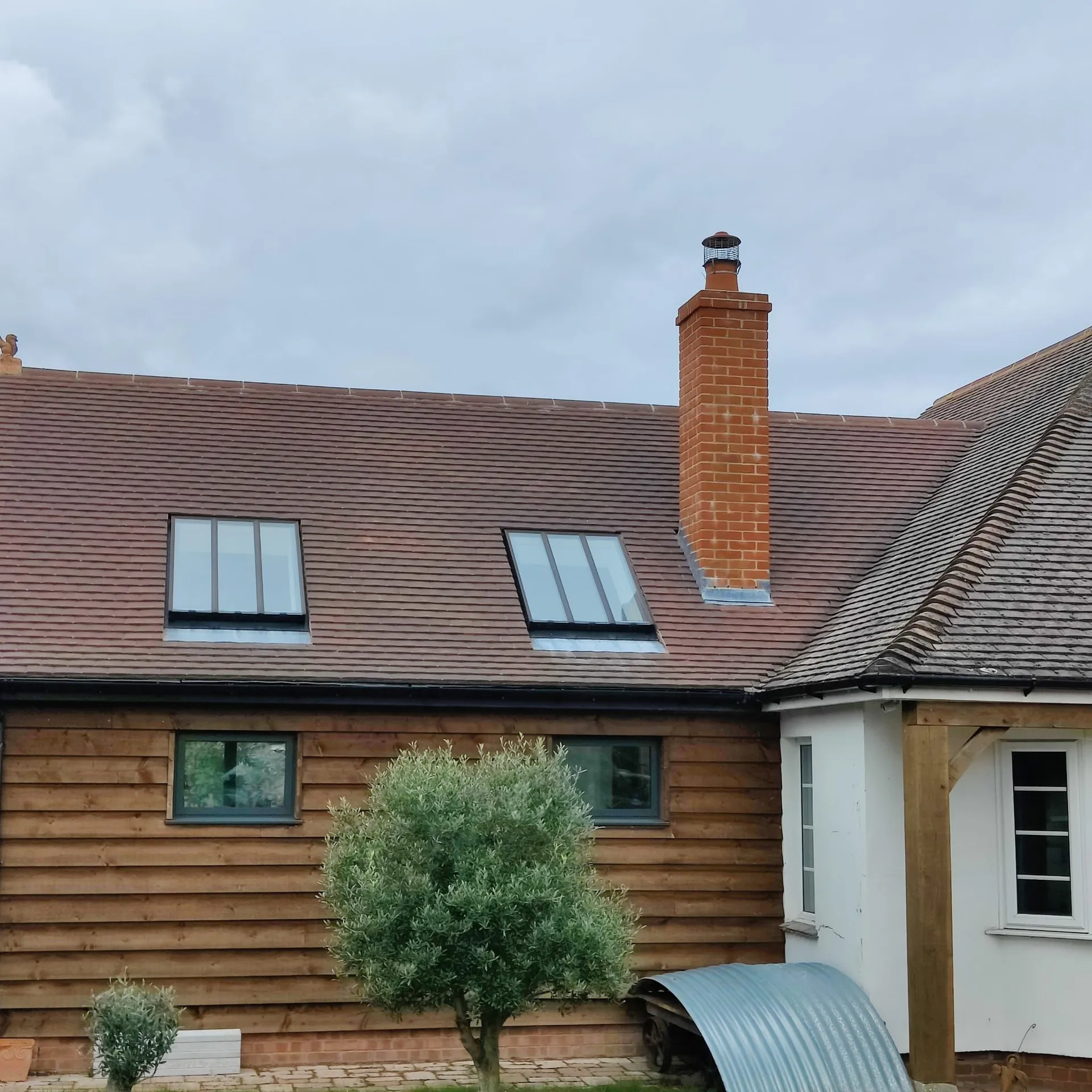 A tiled roof and chimney on a brick house